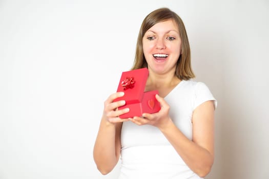 Portrait of a happy smiling pretty girl opening a red present box on the white background. Valentines day concept.