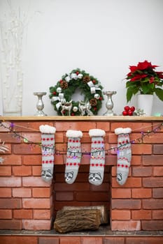 Decoration on the wooden shelf. Fireplace made of bricks and warm socks.