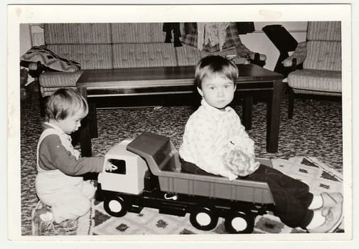 THE CZECHOSLOVAK SOCIALIST REPUBLIC - CIRCA 1970s: Retro photo shows children who play with toy car. Black white vintage photography.