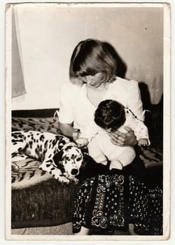 THE CZECHOSLOVAK SOCIALIST REPUBLIC - CIRCA 1970s: Retro photo shows child, mother and dog who sit on sofa. Black and white vintage photography.