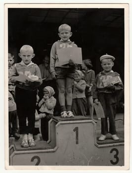 THE CZECHOSLOVAK SOCIALIST REPUBLIC - CIRCA 1960s: Retro photo shows children (boys) who stand on winners' podium. Black and white vintage photography.