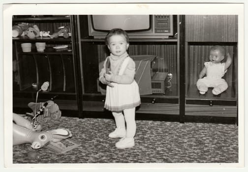 THE CZECHOSLOVAK SOCIALIST REPUBLIC - CIRCA 1970s: Retro photo shows child, girl who plays with toy. Black and white vintage photography.