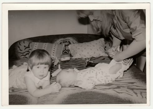 THE CZECHOSLOVAK SOCIALIST REPUBLIC - CIRCA 1970s: Retro photo shows mother puts on the baby. Black and white vintage photography.