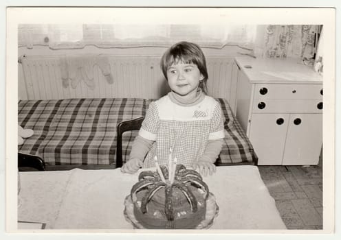 THE CZECHOSLOVAK SOCIALIST REPUBLIC - CIRCA 1970s: Retro photo shows small girl during her birthday three years old. Black and white vintage photography.