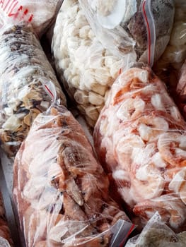 There are many large plastic bags with frozen raw and boiled shrimp on the counter of the fish market