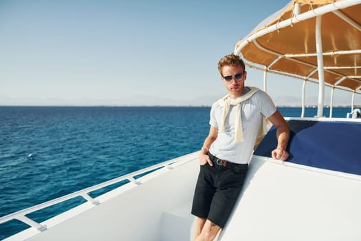 Young male tourist is on the yacht on the sea. Conception of vacation.