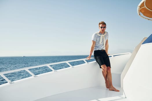 Young male tourist is on the yacht on the sea. Conception of vacation.