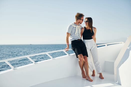 Cheerful young couple standing on the yacht on the sea. Conception of vacation.