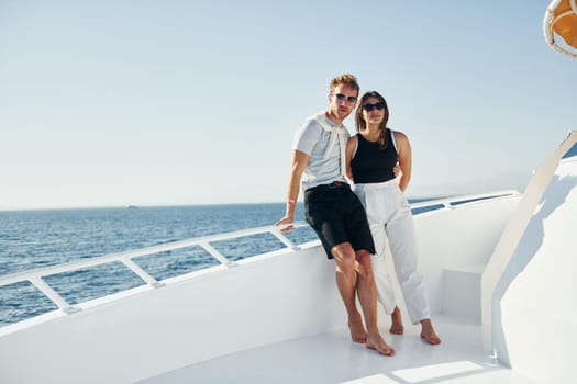 Cheerful young couple standing on the yacht on the sea. Conception of vacation.