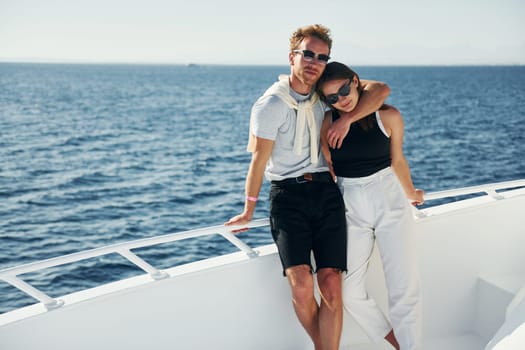 Cheerful young couple standing on the yacht on the sea. Conception of vacation.