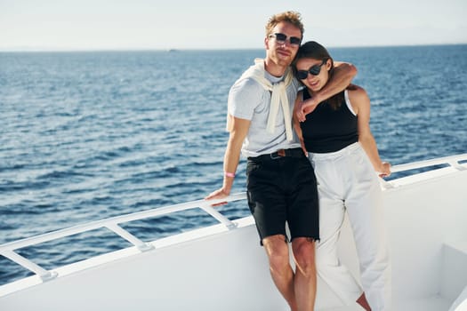 Cheerful young couple standing on the yacht on the sea. Conception of vacation.