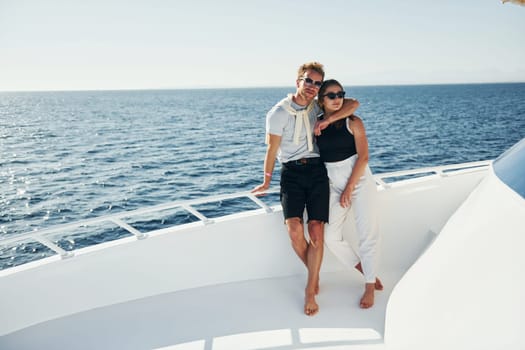 Cheerful young couple standing on the yacht on the sea. Conception of vacation.