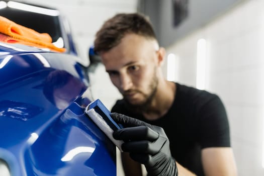 Process of applying ceramic protective coat on body car using sponge in detailing auto service. Car service worker apply ceramic coating to protect the car body from scratches