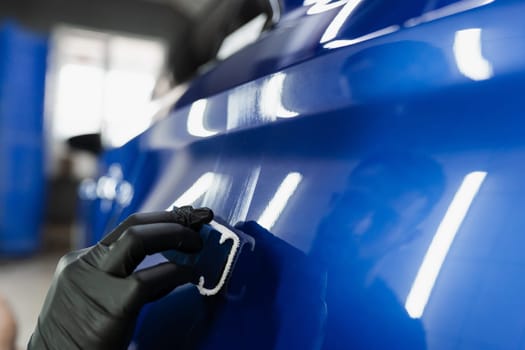 Close-up process of apply ceramic layer on body car using sponge in detailing auto service. Hand applying of nano ceramic protective coat to protect car from scratches