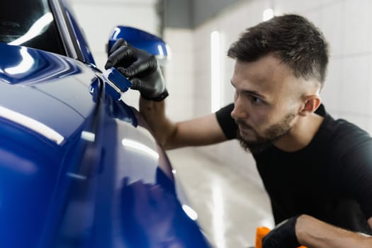 Detailing service worker applies ceramic protective liquid on car. Hand applying of nano ceramic protective coat to protect car from scratches