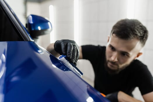 Process of applying ceramic protective coat on body car using sponge in detailing auto service. Car service worker apply ceramic coating to protect the car body from scratches