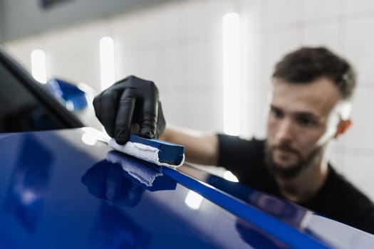 Detailing service worker applies ceramic protective liquid on car. Hand applying of nano ceramic protective coat to protect car from scratches