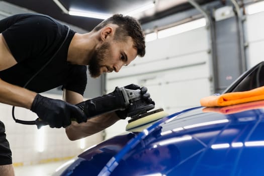 Car polishing with orbital polisher for remove scratches. Worker of detailing auto service making final polishing for car