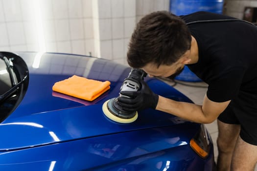 Abrasive paste car polishing with orbital polisher for remove scratches. Worker of detailing auto service making final polishing for car