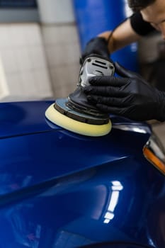Hard wax car polishing with orbital polisher for remove scratches close-up. Working process in detailing auto service