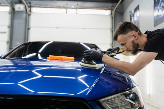 Hard wax car polishing with orbital polisher for remove scratches close-up. Working process in detailing auto service