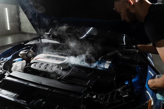 Steaming washing of motor of auto in detailing auto service. Process of steam cleaning car engine from dust and dirt