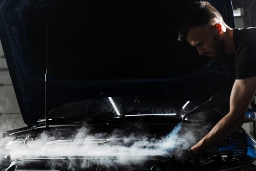 Steaming washing of motor of auto in detailing auto service. Process of steam cleaning car engine from dust and dirt