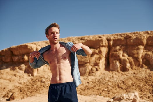 Shows body. Young european man have vacation and enjoying free time on the beach of sea.