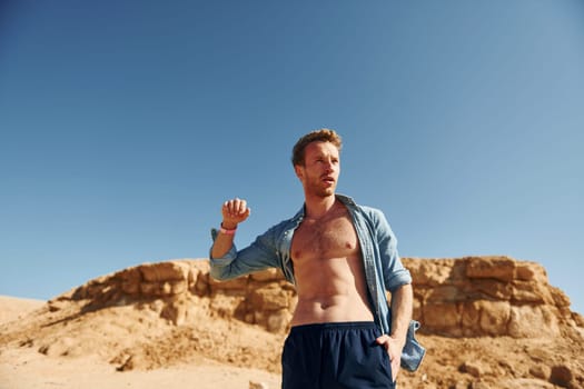 Shows body. Young european man have vacation and enjoying free time on the beach of sea.