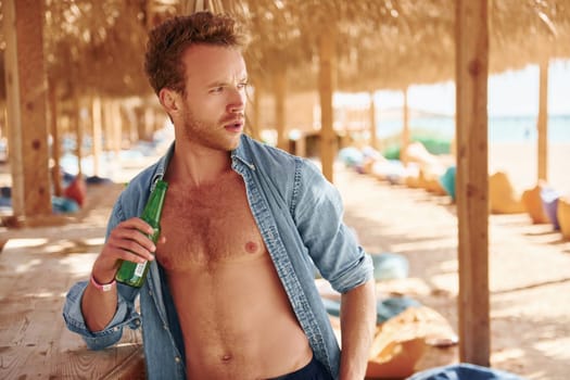 Shows body. Young european man have vacation and enjoying free time on the beach of sea.