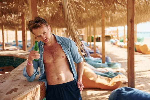 Shows body. Young european man have vacation and enjoying free time on the beach of sea.