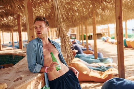 Shows body. Young european man have vacation and enjoying free time on the beach of sea.