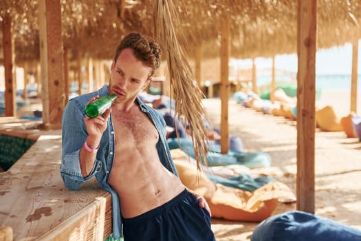 Shows body. Young european man have vacation and enjoying free time on the beach of sea.