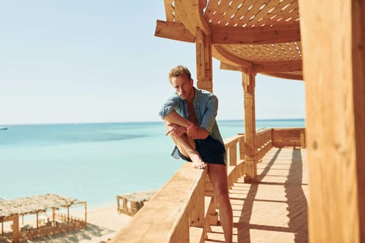 Wooden building. Young european man have vacation and enjoying free time on the beach of sea.
