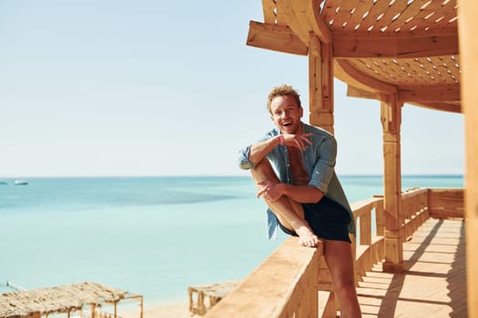 Wooden building. Young european man have vacation and enjoying free time on the beach of sea.