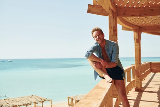 Wooden building. Young european man have vacation and enjoying free time on the beach of sea.