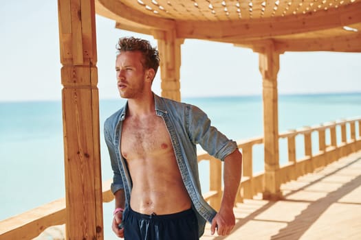 Wooden building. Young european man have vacation and enjoying free time on the beach of sea.