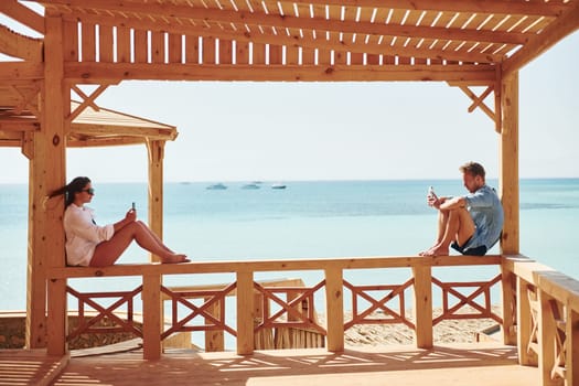 Young man and woman sitting on the beach of the sea. Conception of vacation.
