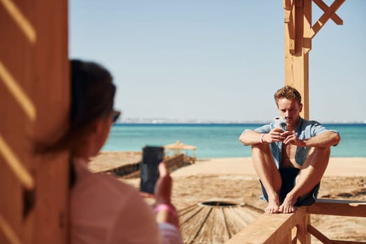 Young man and woman sitting on the beach of the sea. Conception of vacation.