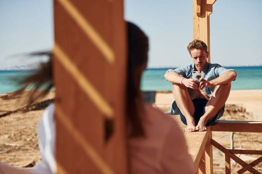Young man and woman sitting on the beach of the sea. Conception of vacation.