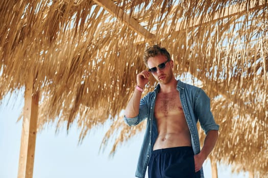 Posing for a camera. Young european man have vacation and enjoying free time on the beach of sea.