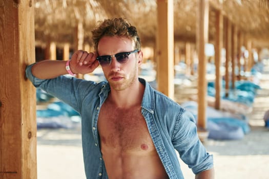 Posing for a camera. Young european man have vacation and enjoying free time on the beach of sea.