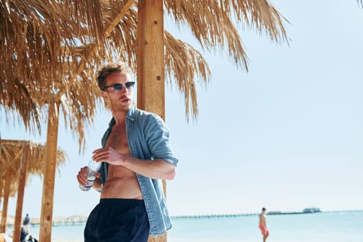 Posing for a camera. Young european man have vacation and enjoying free time on the beach of sea.