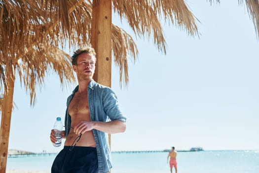 Posing for a camera. Young european man have vacation and enjoying free time on the beach of sea.