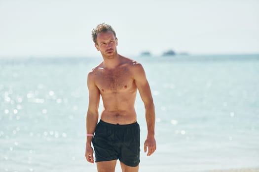 Clear water. Young european man have vacation and enjoying free time on the beach of sea.