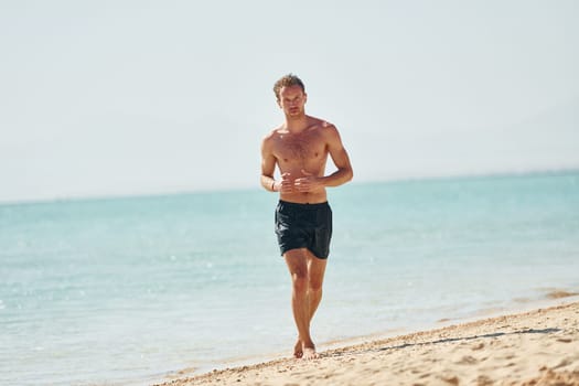 Clear water. Young european man have vacation and enjoying free time on the beach of sea.