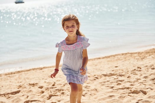 Little girl have vacation on the sea at sunny daytime. Conception of travel.