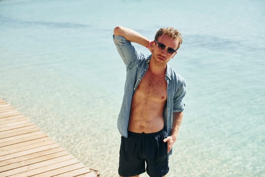 In sunglasses. Young european man have vacation and enjoying free time on the beach of sea.