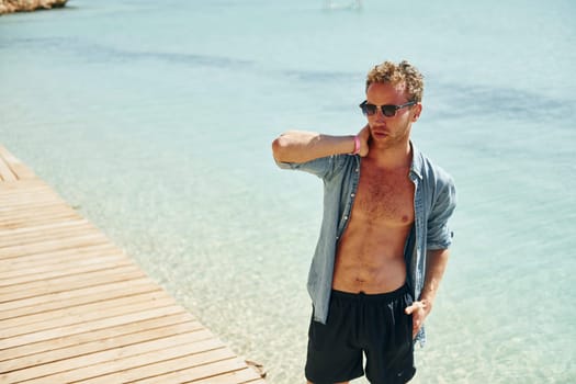 In sunglasses. Young european man have vacation and enjoying free time on the beach of sea.