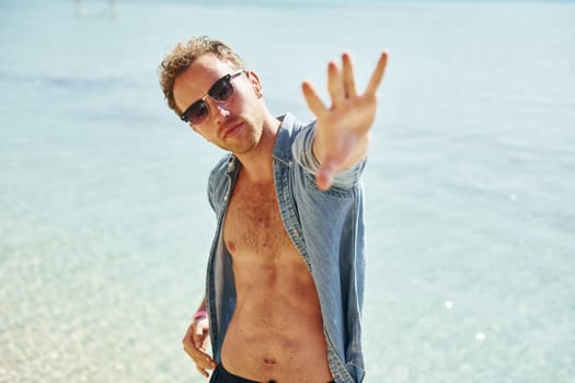 In sunglasses. Young european man have vacation and enjoying free time on the beach of sea.